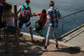 En dreng, der rg i vandet med skoletaske, cykel mv., hales p land.